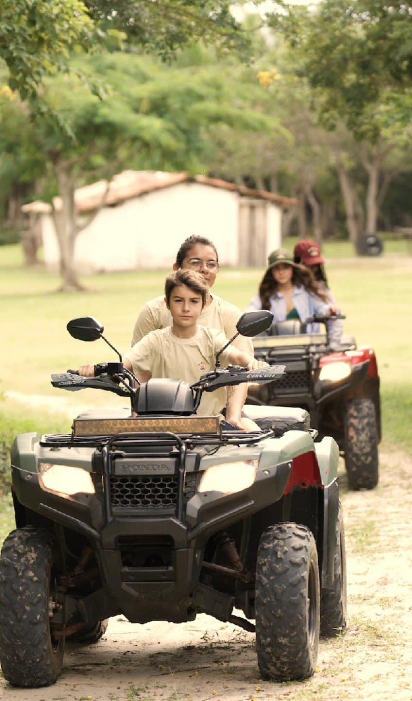 Família atravessando a fazenda de quadriciclo