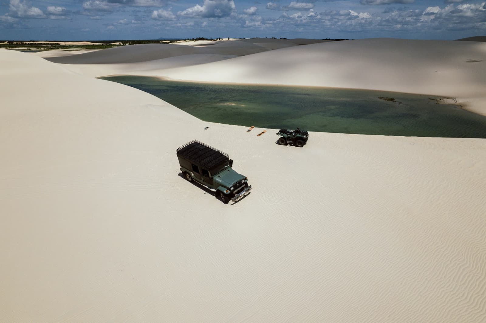 Jipe atravessando as dunas, ao lado de uma lagoa