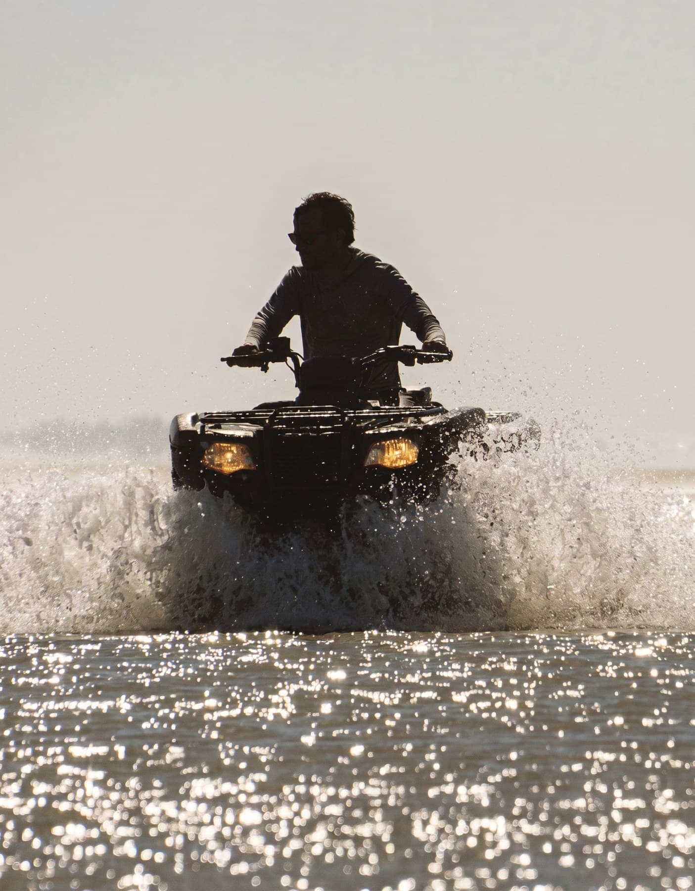 Quadriciclo cruzando a água rasa, na beira da praia
