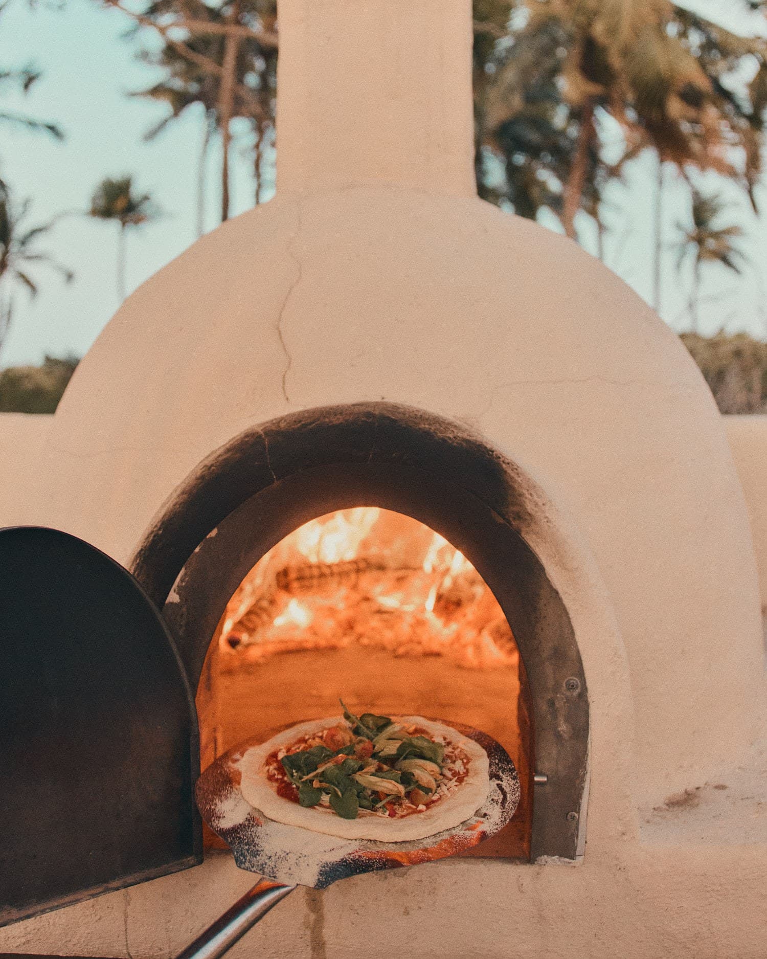 O forno de barro da Pizzaria Moréias, com a pizza entrando na brasa